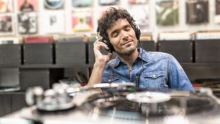 hero image for best gifts for music lovers showing man listening to music in a record store