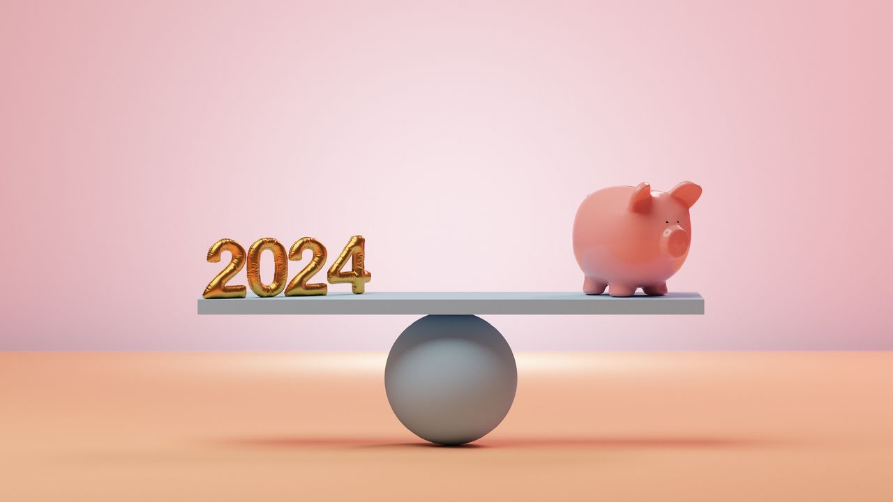 &quot;2024&quot; is on one end of a balanced seesaw, and a piggy bank is on the other. 