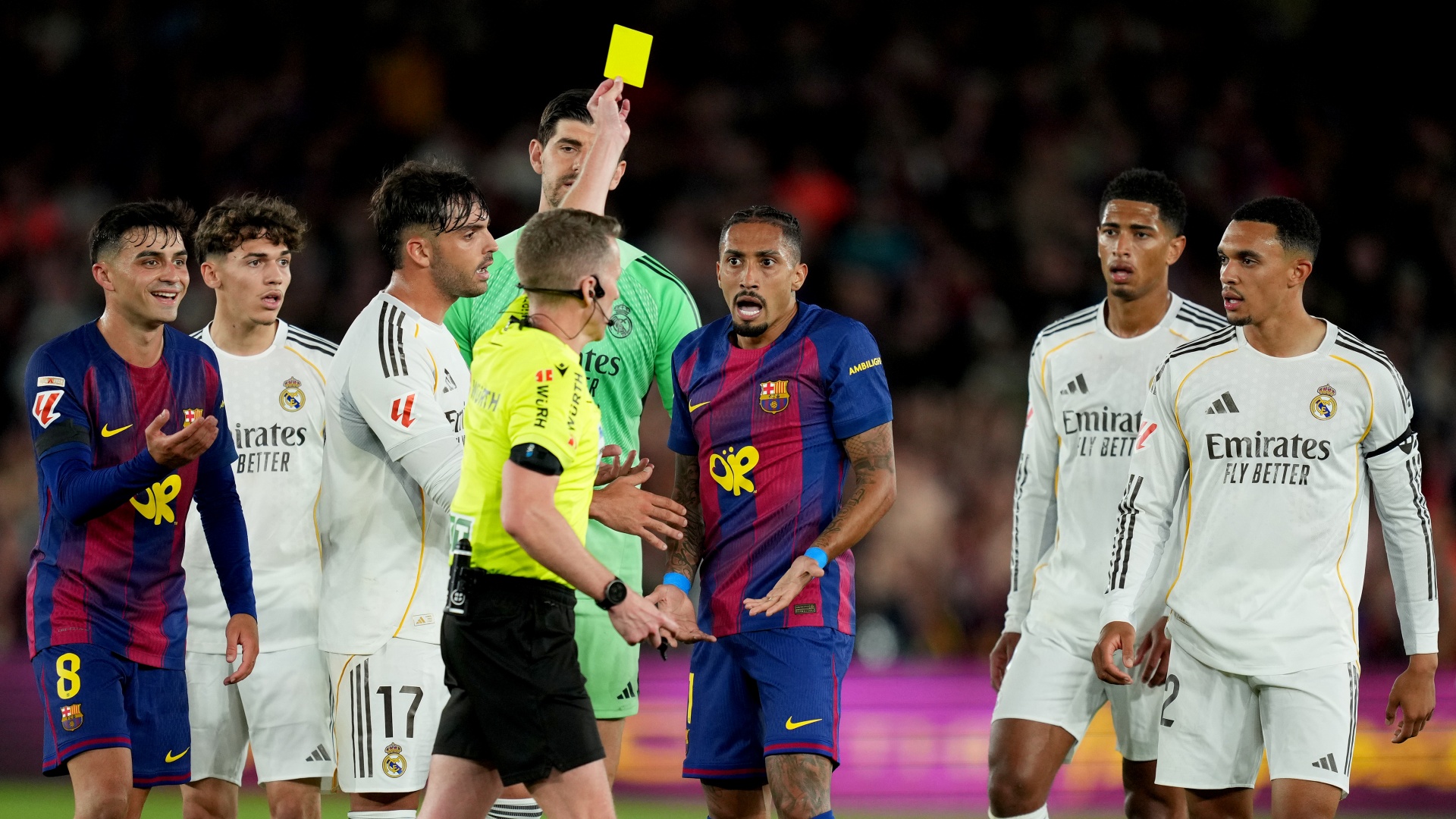 The referee showing Raphinha a yellow card against Real Madrid