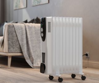 Close-up view of an electric white space heater warming a living room, with blurred couch in the background