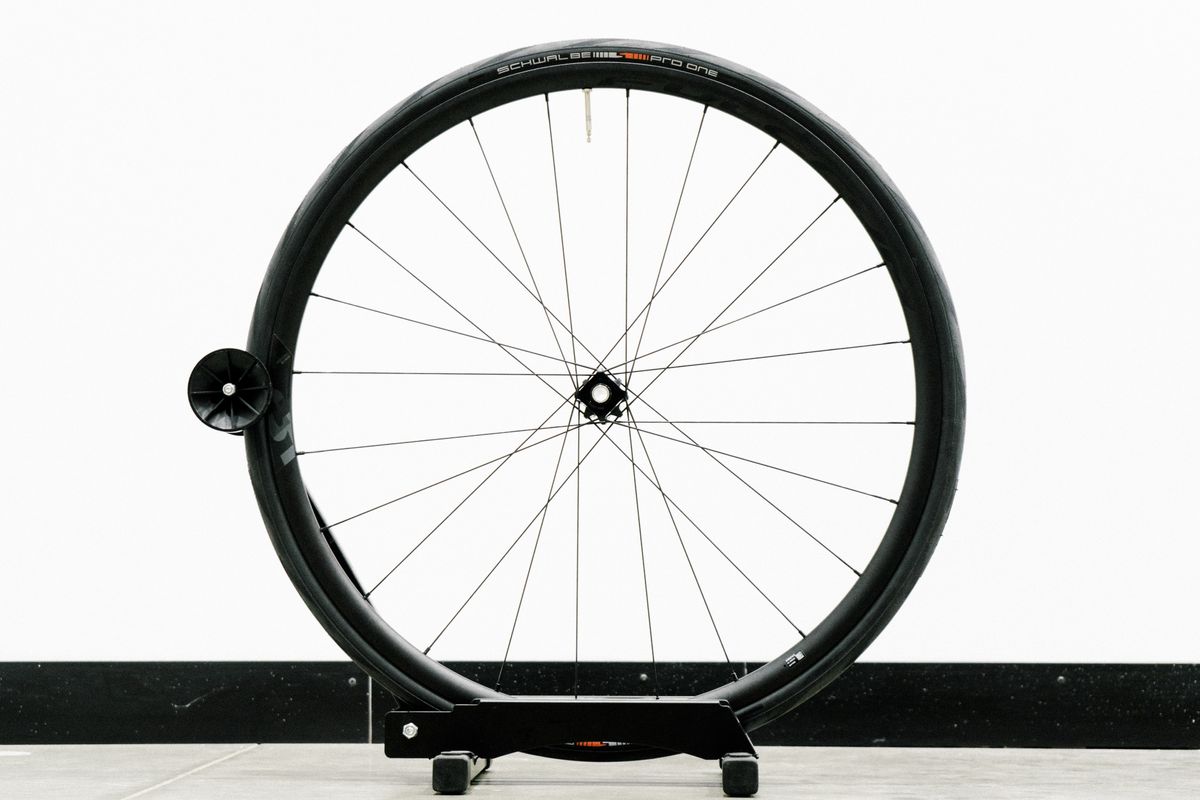 An aero road wheel stands against a white wall