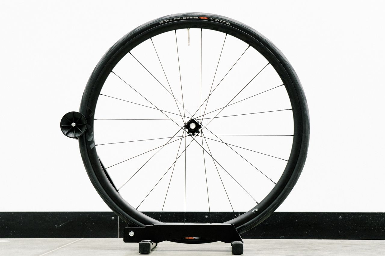 An aero road wheel stands against a white wall