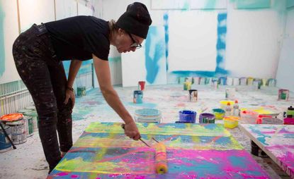 Artist Maya Hayuk is working on a painting in the studio. The painting is made out of different bright colors.