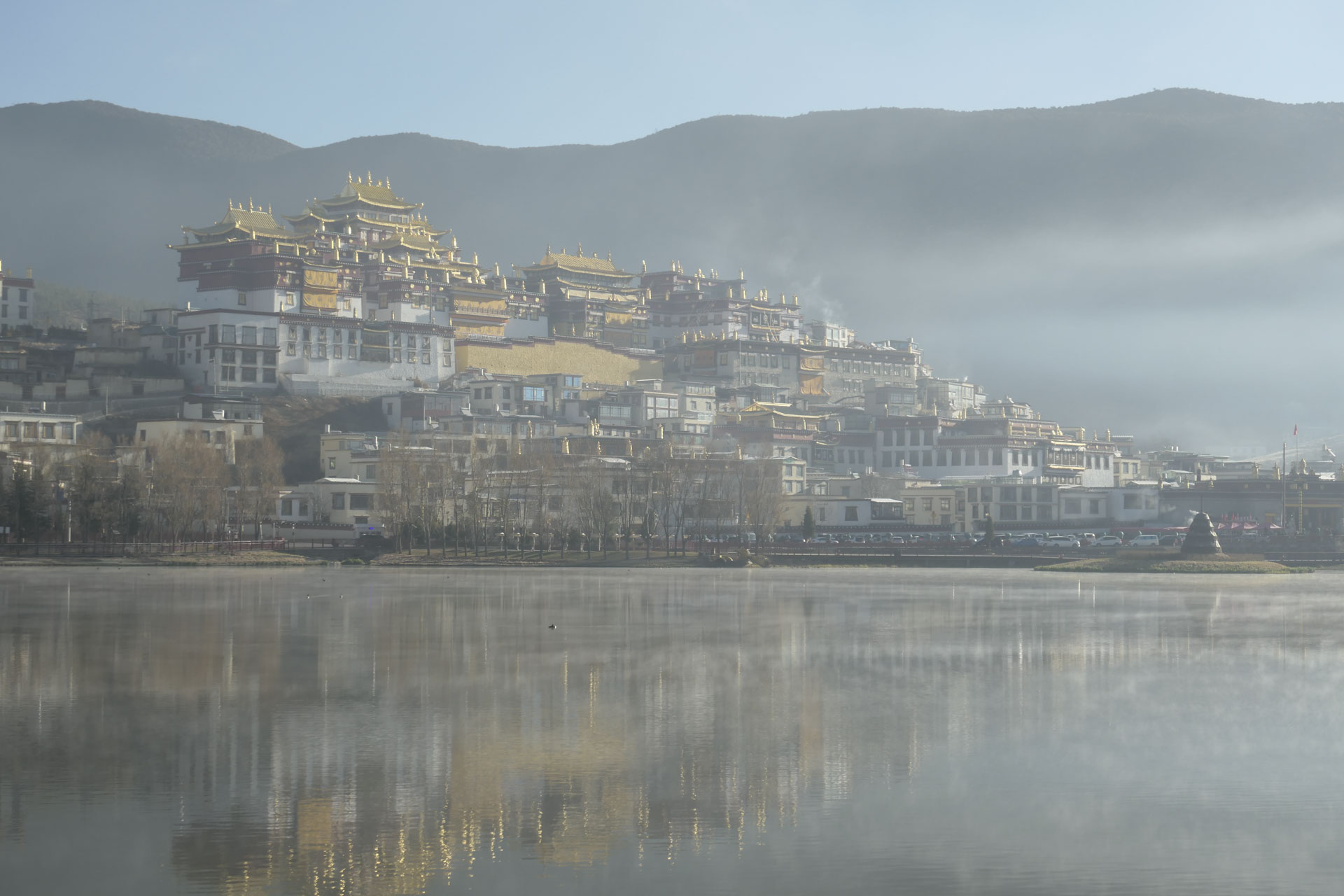 A Chinese monastery reflected in a still lake at first light, with a touch of mist