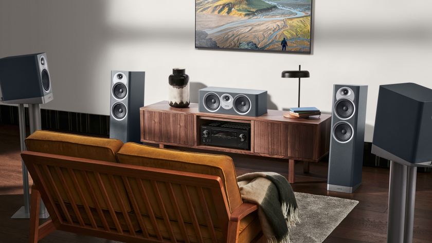 A living room with multiple speakers connected and a TV wall-mounted