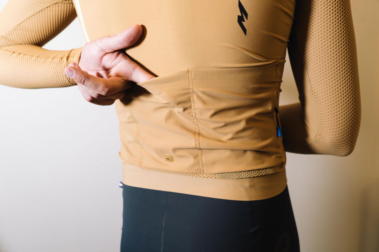 A white man in a tan jersey against a white wall