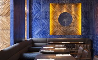 Babaji restaurant tiled tapestry of ink blue and gold on end wall, brown tables and chairs