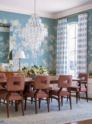 Blue dining room with chandelier, wood table and chair and blue and white wallpaper