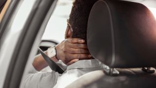 Rear View Of a Man Having Neck Pain While Driving a Car