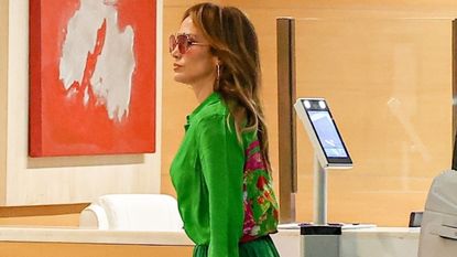 Jennifer Lopez wearing a green floral blouse with a matching maxi skirt, platform heels, and a pink custom Valentino purse in Los Angeles September 2024