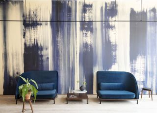 Wallpaper with hand-painted blue stripes with furniture display including two blue velvet sofas