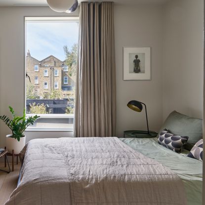 A bedroom with a large window overlooking an apartment building