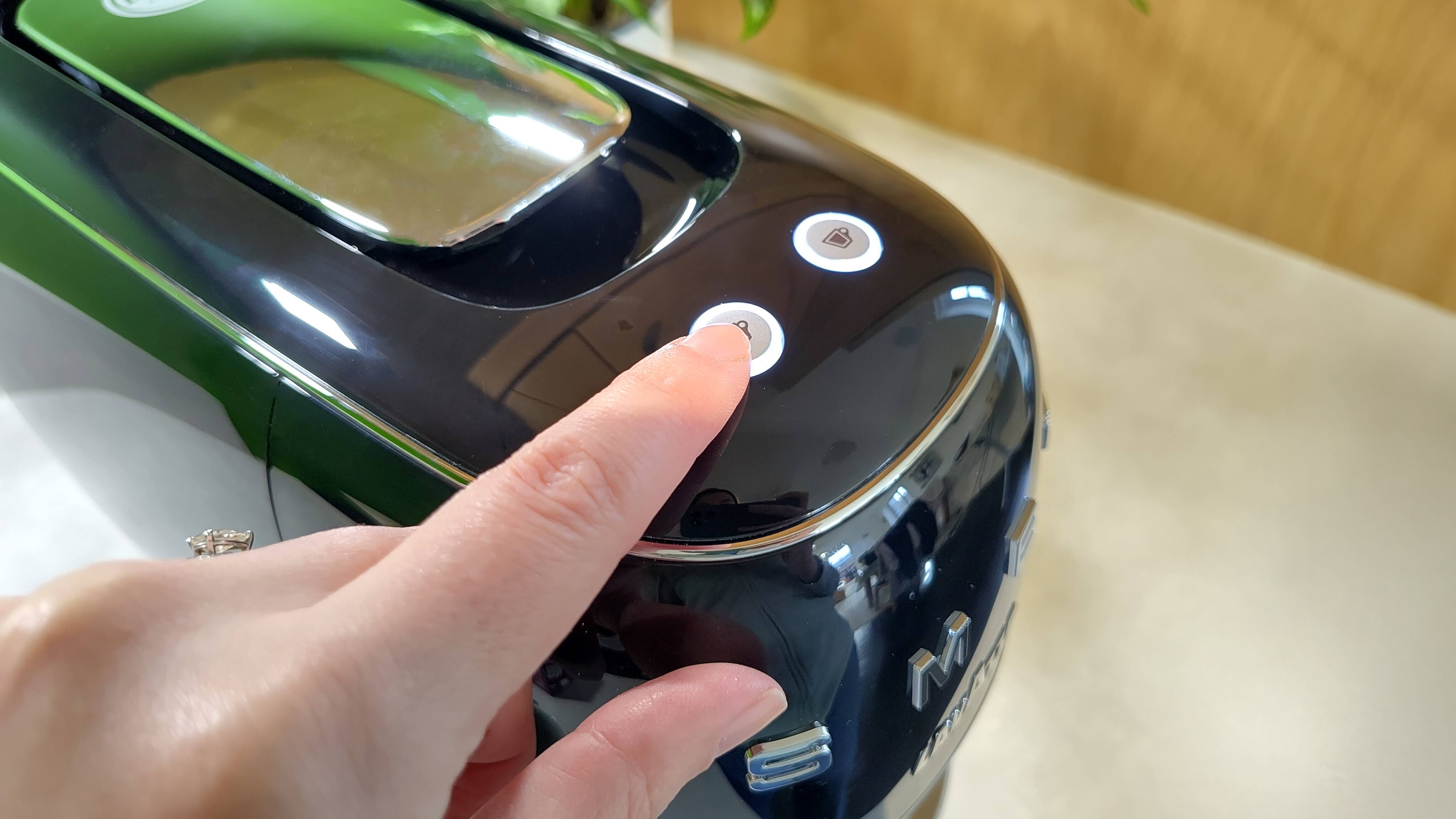 Person pressing button on Lavazza A Modo Mio Smeg coffee maker