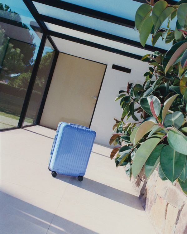A sea blue minimalist cabin suitacase is captured in multiple sun-lit settings.