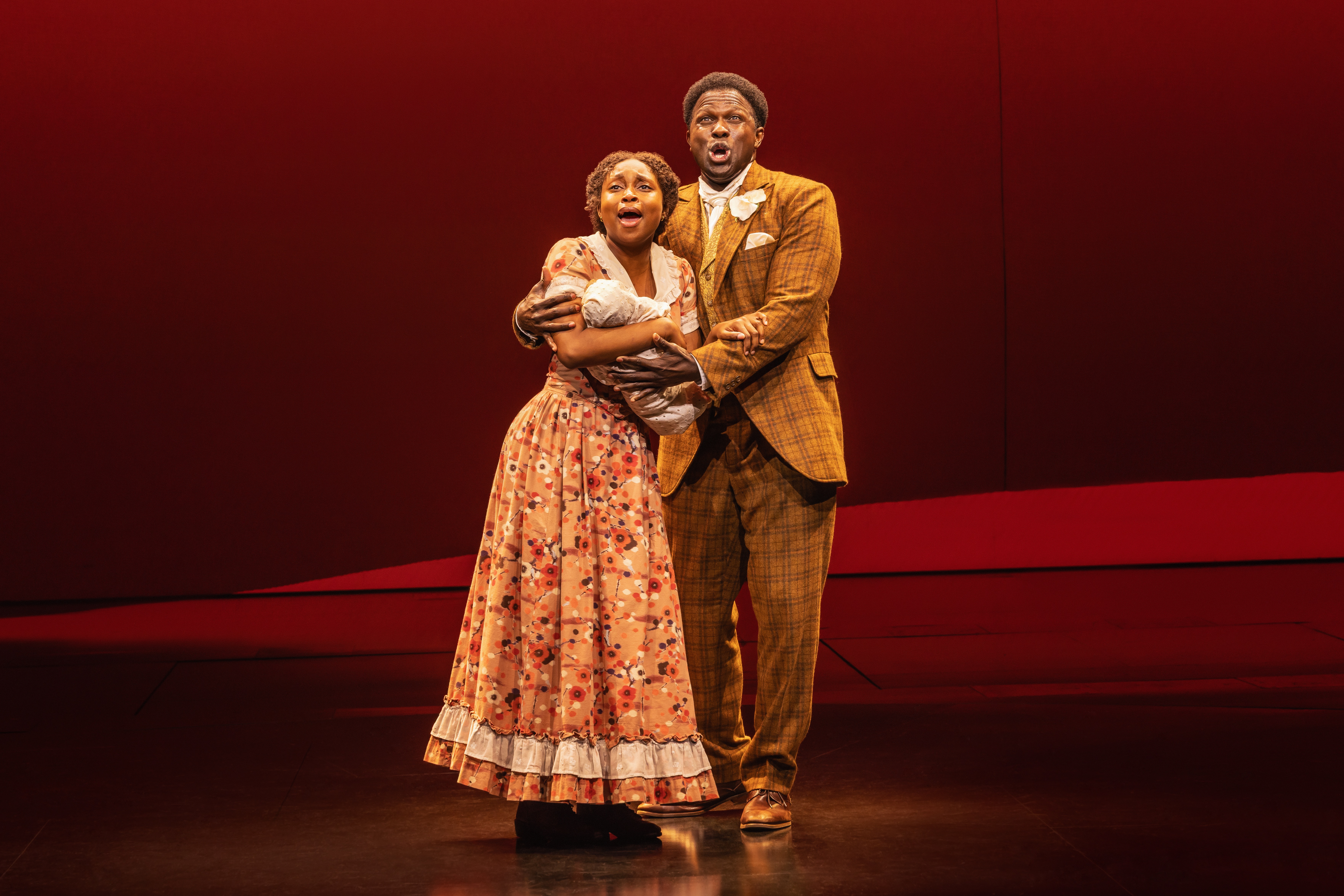 nichelle lewis and joshua henry on stage in early 20th century clothing holding each other and a baby in the musical ragtime