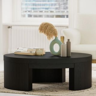 A black circular coffee table with decorative accessories on top