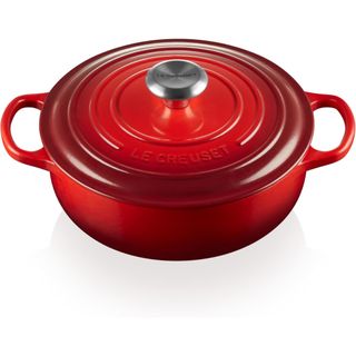 A bright red cast iron dutch oven pan with a silver lid handle 