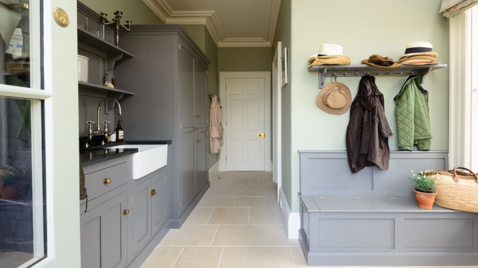 A boot room with gray cabinets, green walls, and large format floor tiles