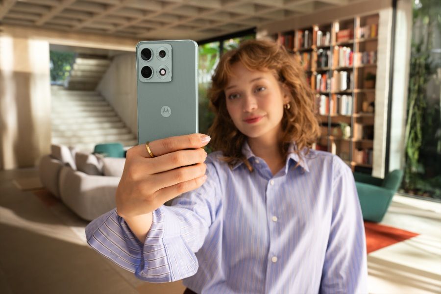 The Motorola Edge 70 Max in Ice Melt in a model's hands in their living room.