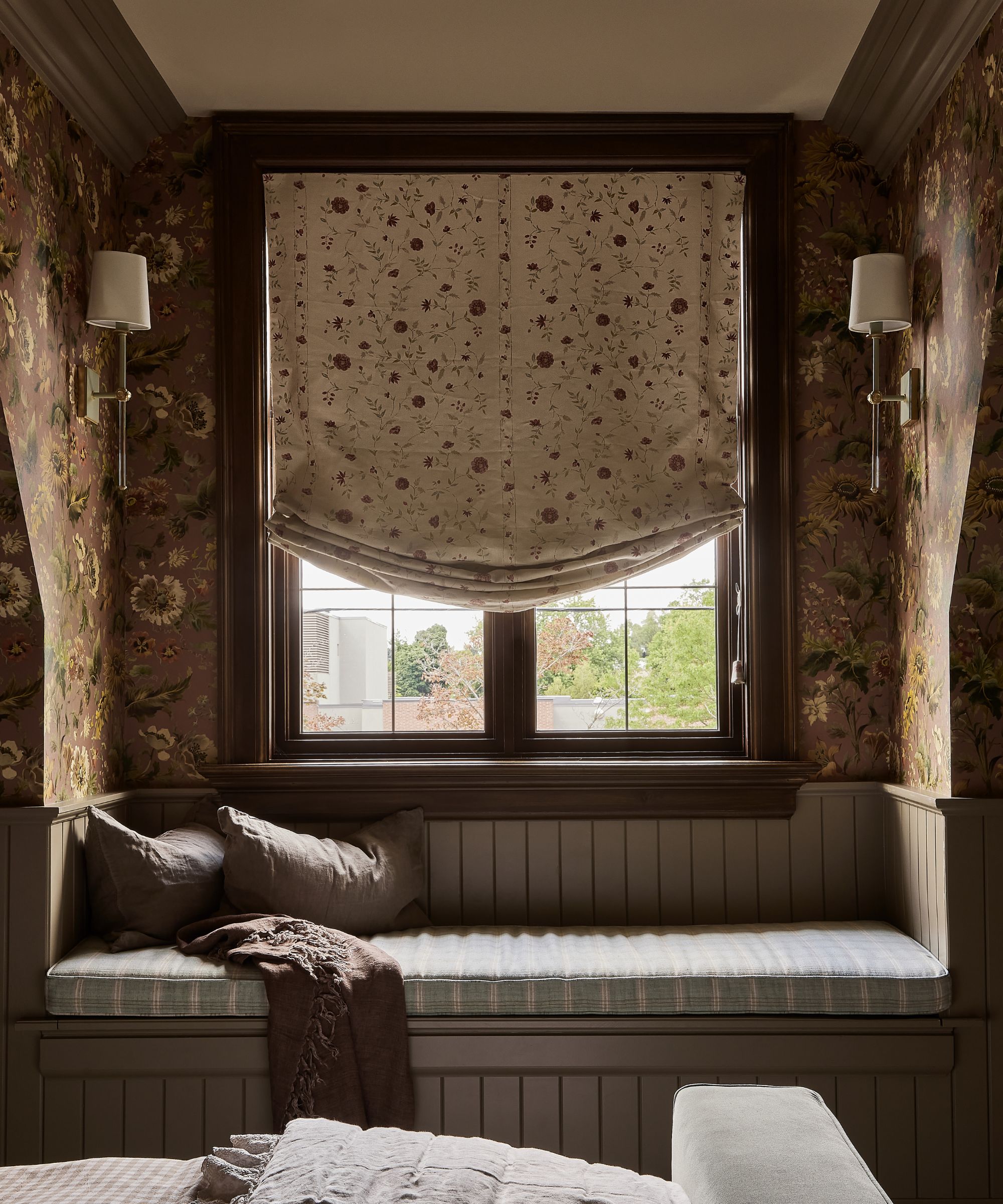 Close up of window nook seat, panelled bench with cushion, patterned blinds and wallpaper