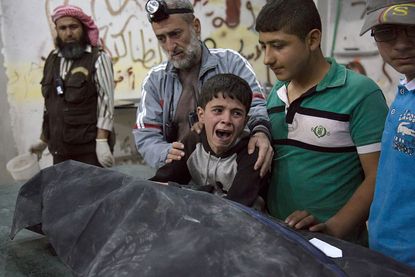 A boy cries over the victim of an airstrike on rebels in Aleppo, Syria