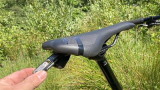 Close up of hand using tool to adjust bike saddle