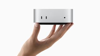 Apple Mac Mini desktop device held in a hand.