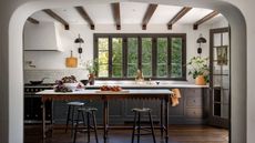 A kitchen with warm black cabinets, white walls, and dark wood floor and a kitchen island. 