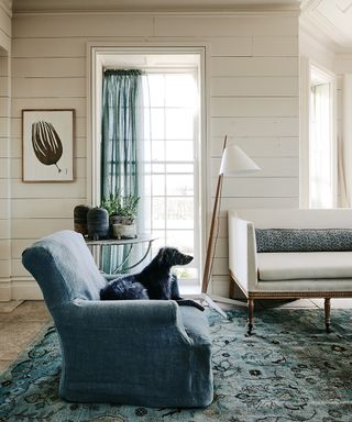 A cream living room with blue armchair and rug.