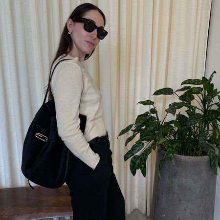 Anna wears a black liffner bag with a long-sleeve shirt, sunglasses, and black pants.