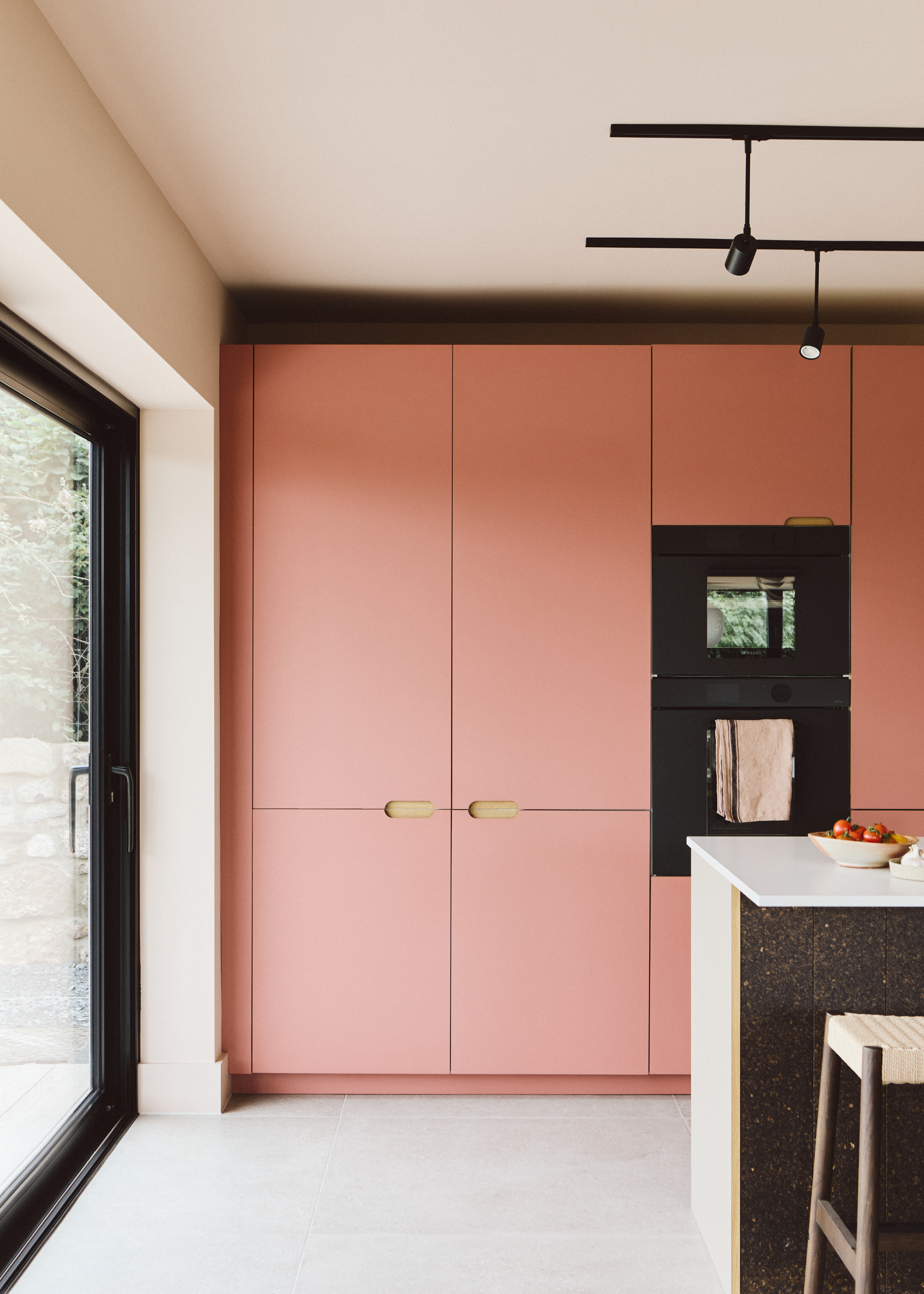 pink cabinetry in a kitchen extension with a corner view of a kitchen island