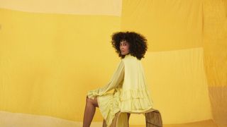 Yellow, Shoulder, Fashion, Furniture, Fashion design, Joint, Sitting, Outerwear, Room, Dress,
