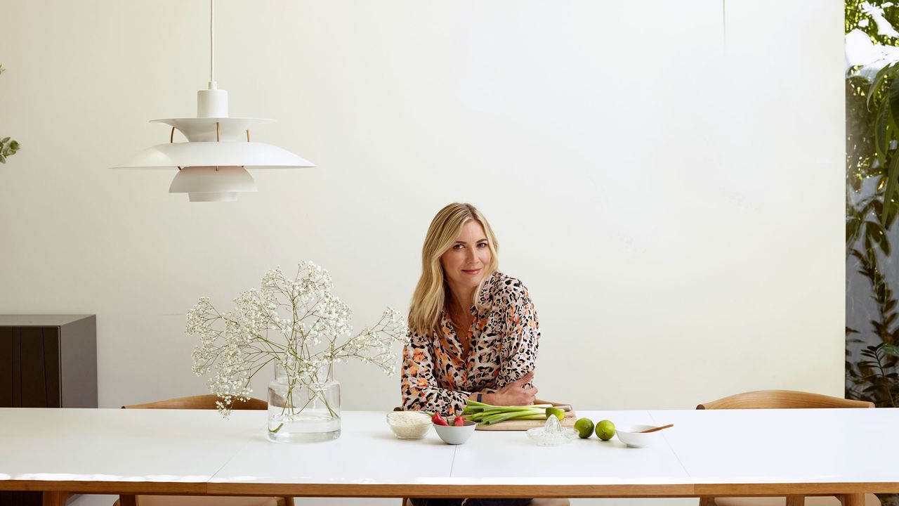 Lisa Faulkner sitting at a table in a dining room with a Louis Poulsen pendant light overhead