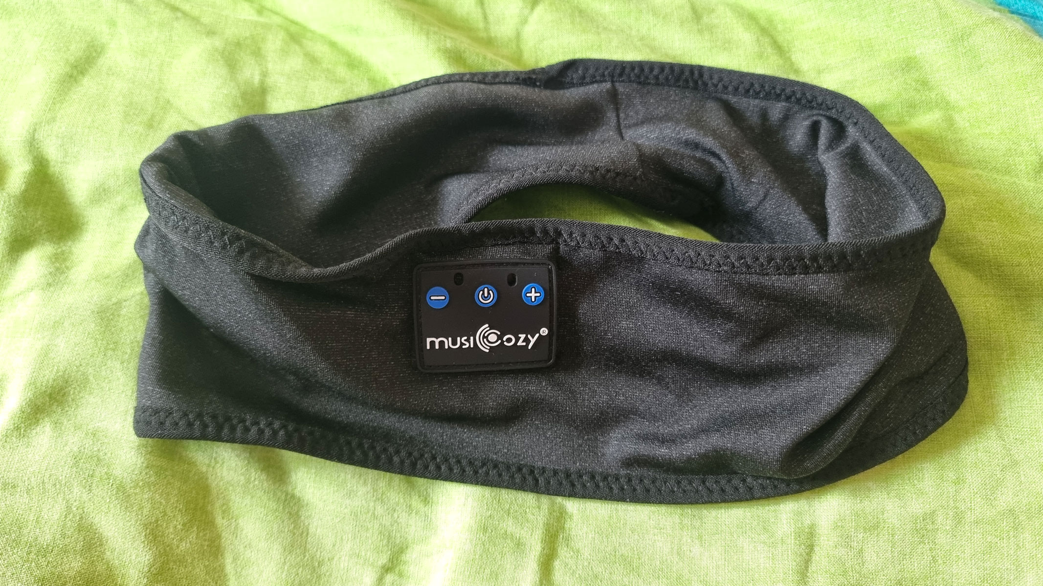 Musicozy Sleep Headphones laid out on a green pillow