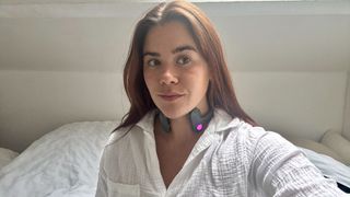 A girl wearing Pulsetto vagus nerve stimulator on neck and white pyjama shirt