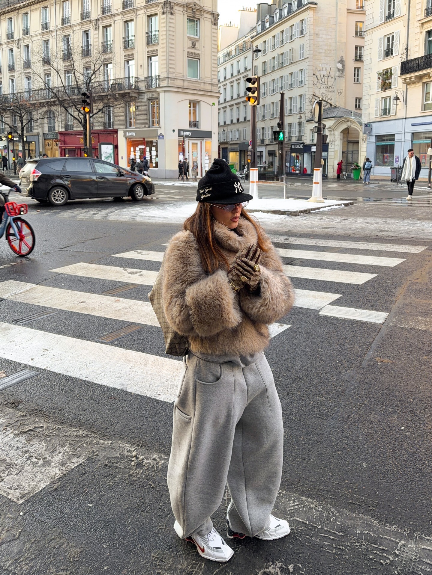 Fashion person sofiamcoelho wears a trending trainer brand 2026. She wears red Nike trainers. She wears them with grey trackies and a brown funnel neck fur. This image was recently taken from her Instagram.