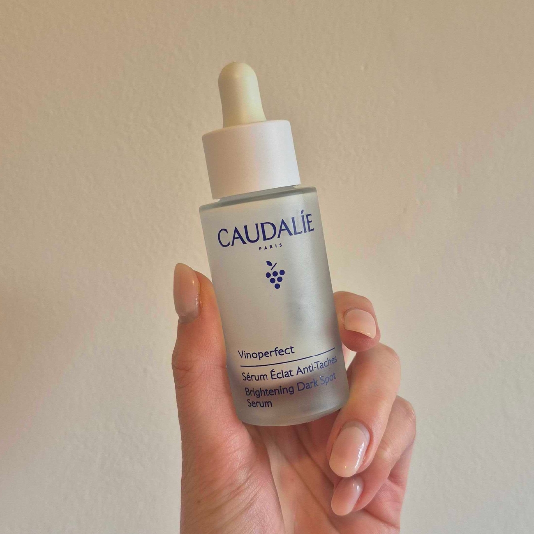 Hand holding empty bottle of Caudalie Vinoperfect Brightening Dark Spot Serum