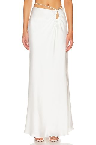 The model is wearing a low-rise white maxi skirt