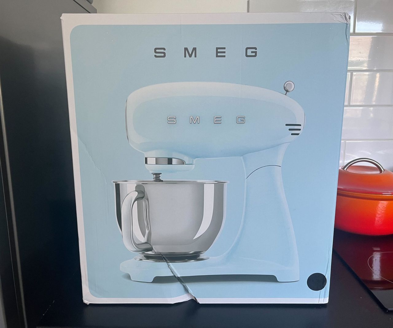 A baby blue SMEG Forte stand mixer box on a black kitchen counter