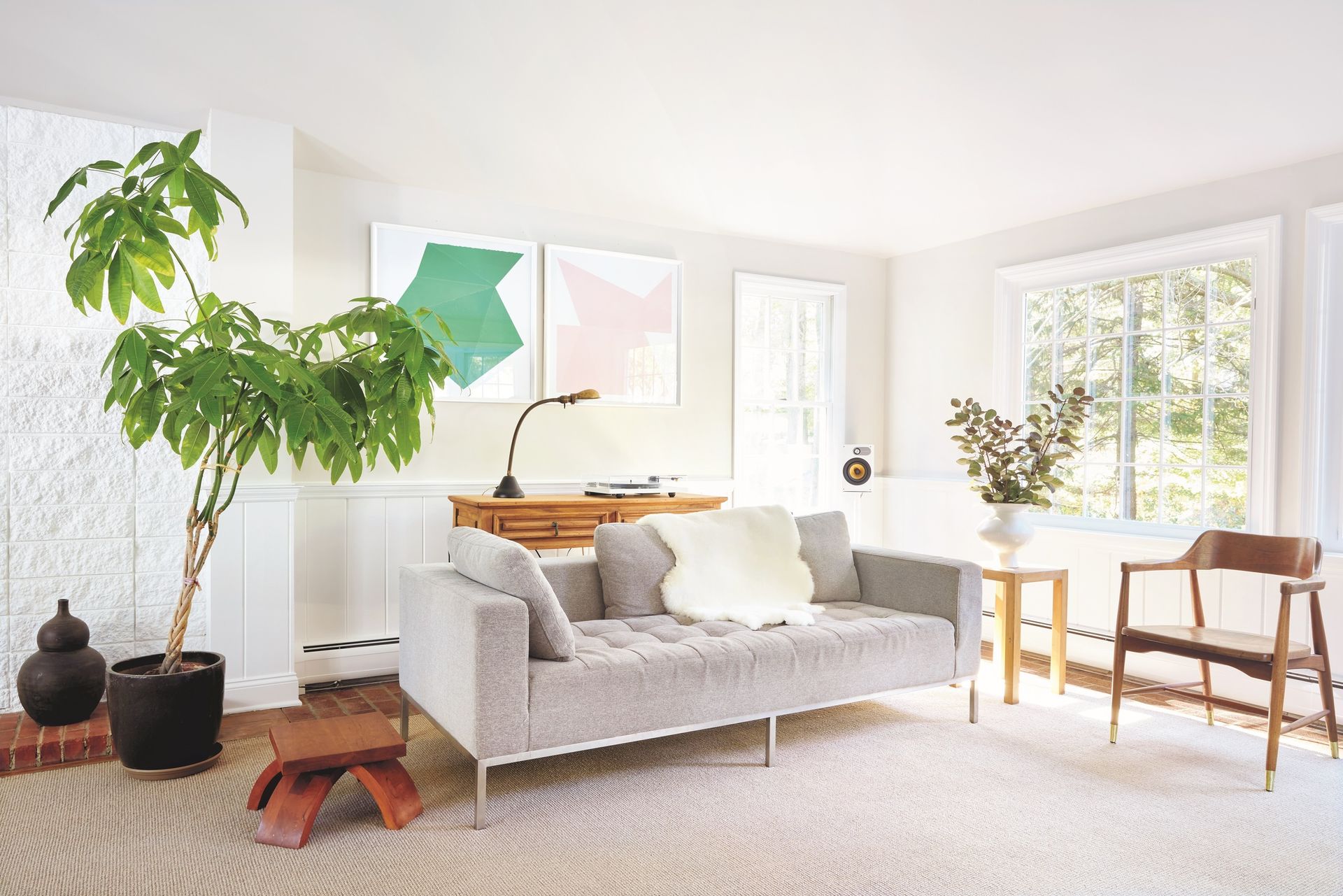 σαλόνι με λευκούς τοίχους, σκούρο γκρι καναπέ και ξύλινο γραφείο πίσω του