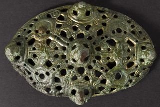 this brooch is partly gilded with gold it contains dozens of tiny incisions along with raised areas and swirling decorations