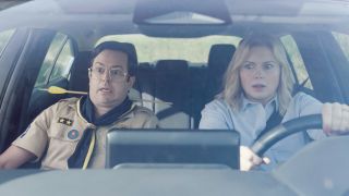 From left to right: Pete in the passenger seat looking scared and Sam driving and looking nervous in Ghosts.