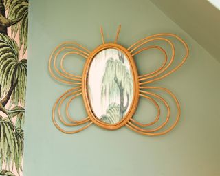 Rattan butterfly mirror on green wall decor by Sass & Belle