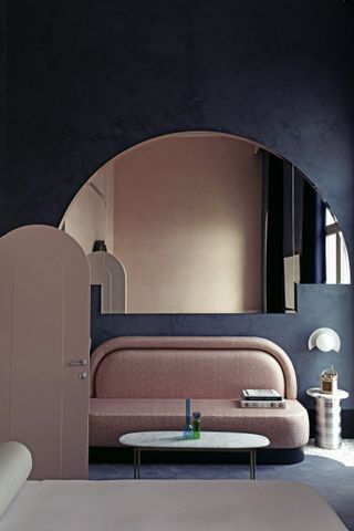 A bedroom with light pink bed and navy blue walls