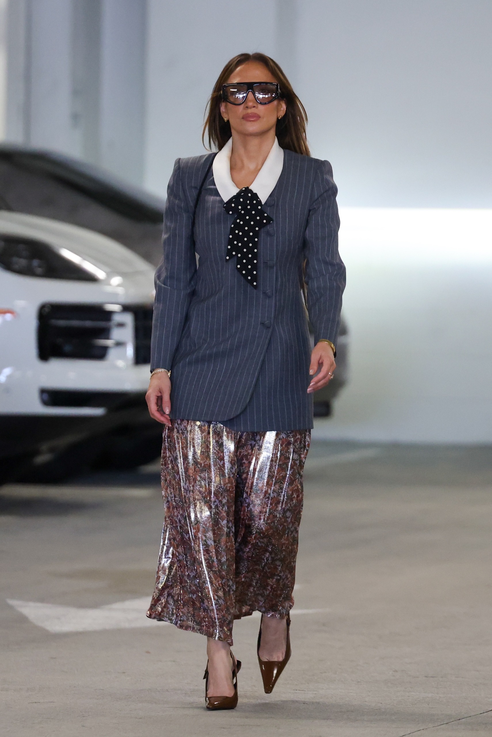Jennifer Lopez wearing a business-like Valentino outfit with the suede bag trend, flipping her golden brown hair