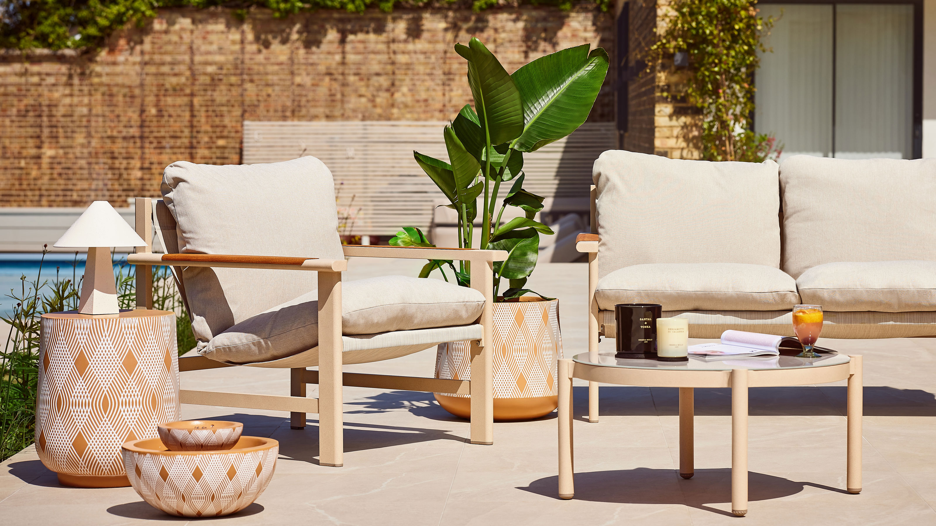 Terracotta water feature on a white patio with beige outdoor dining set