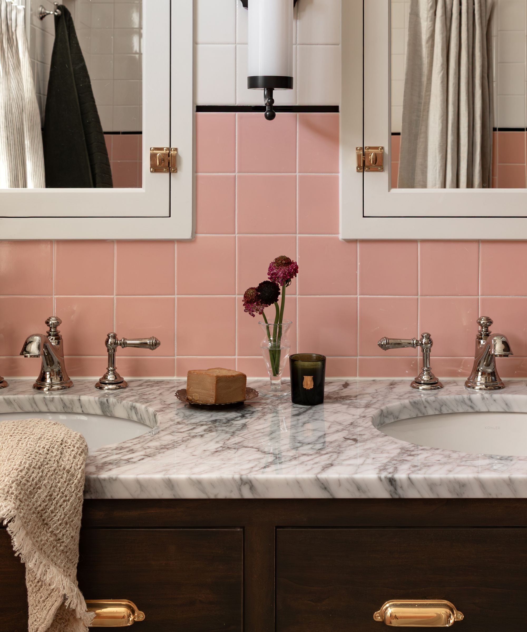 vintage 1940s style bathroom with half pink and white bathroom wall tiles and dark wood cabinetry with a double marble topped vanity