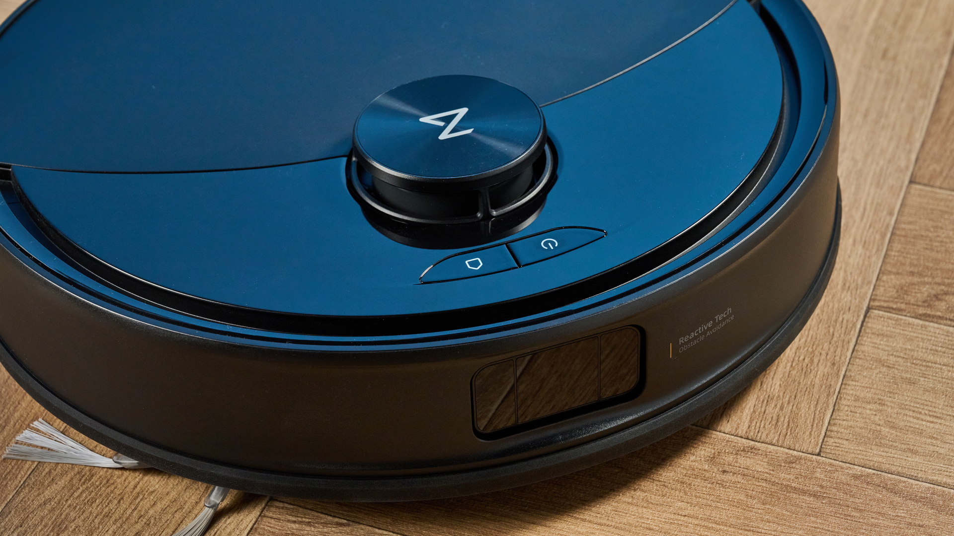 Roborock Q10 S5+ photographed on a wooden floor in front of a blue background