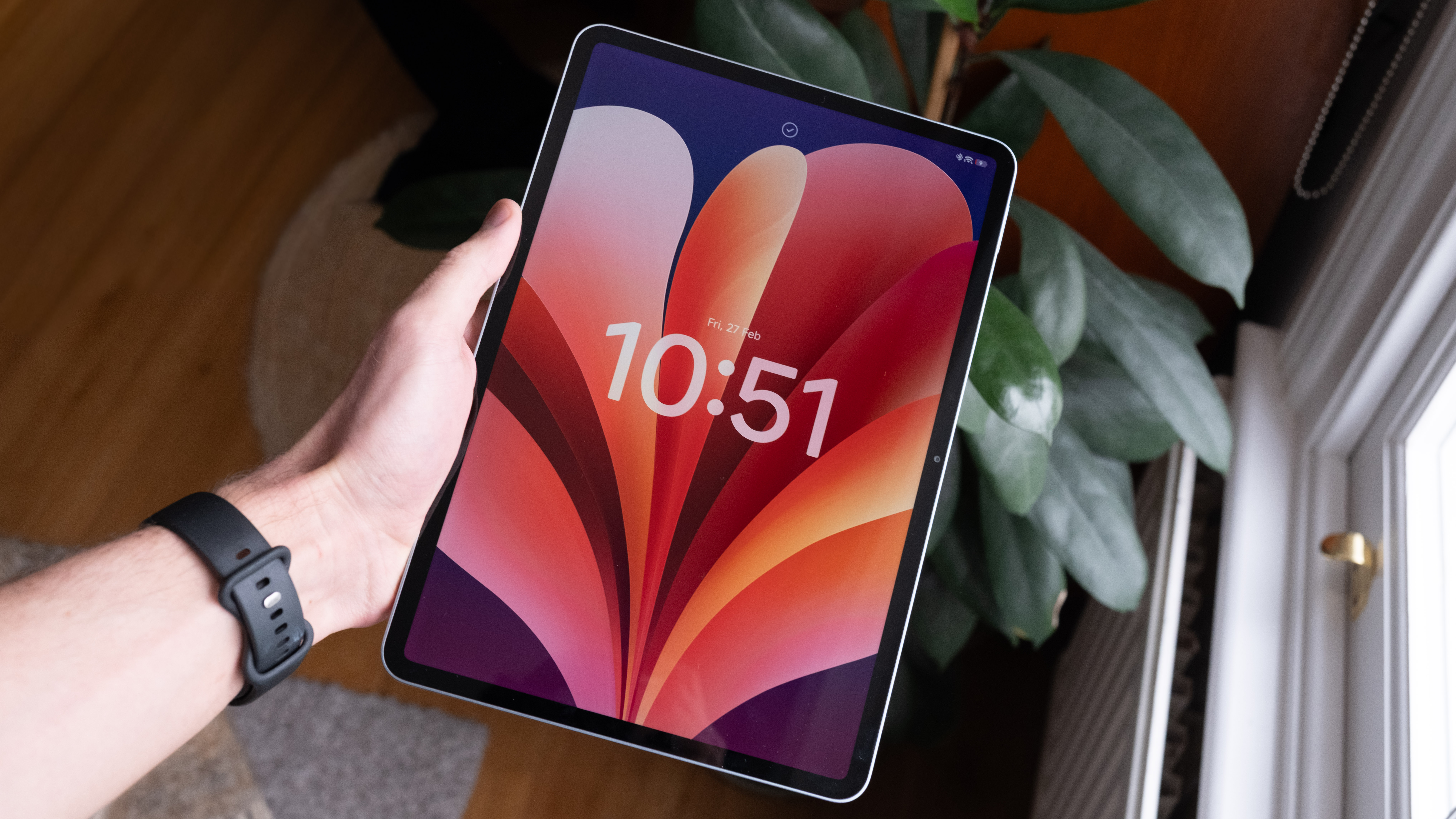 Hand holding the Xiaomi Pad 8 Pro upright near a window, showing the thin bezels and bright display.