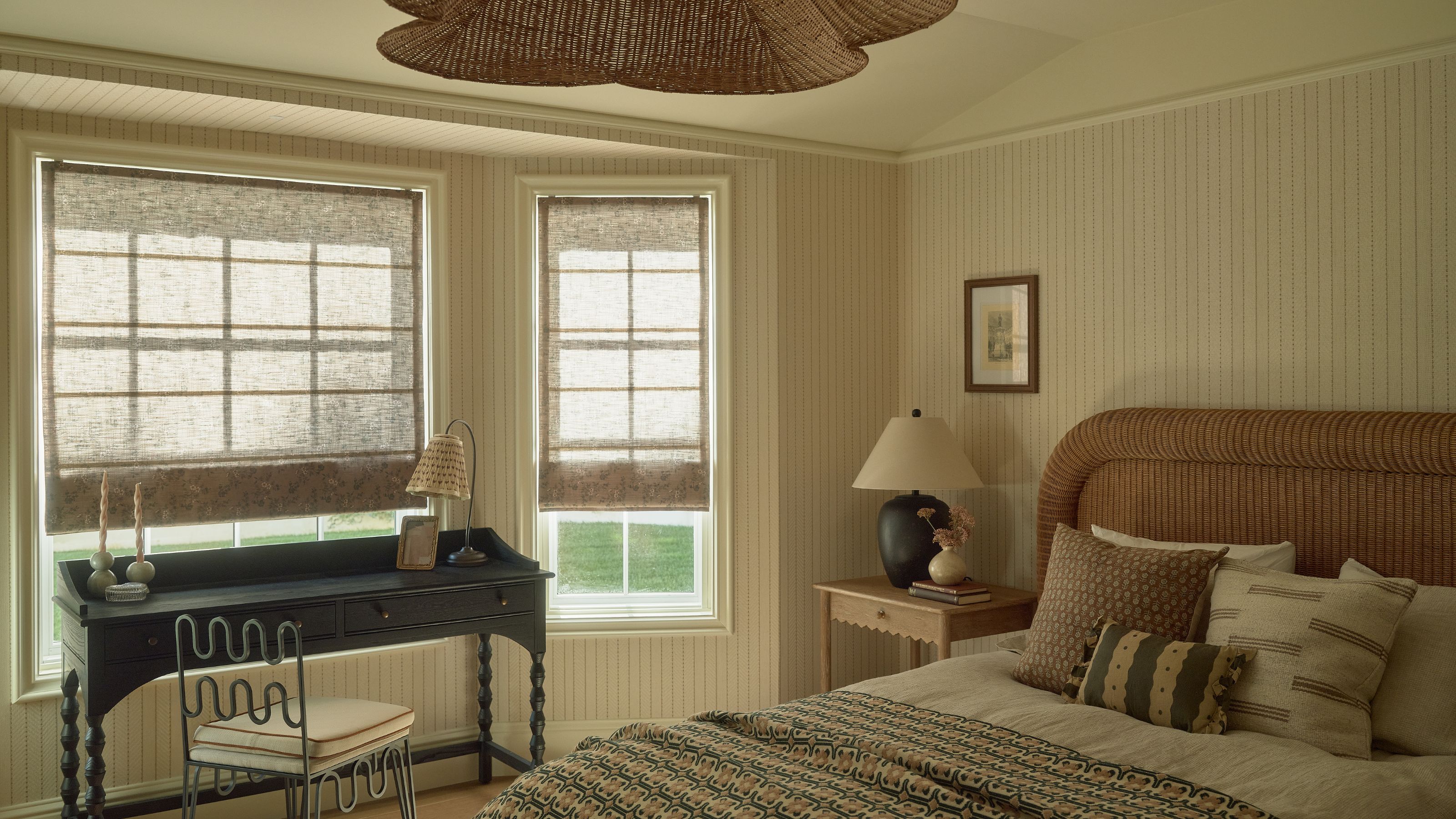 a soft paneled bedroom with a chunky rattan bed and a black twisted leg desk with wavy chair